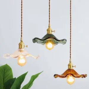 Three Kinney pendant lights in clear, amber, and green fluted glass hanging together with twisted cord over potted plant