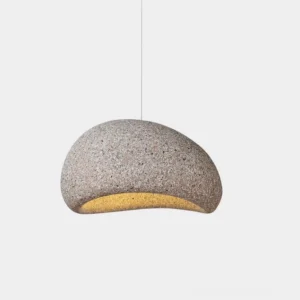 Kioto speckled stone pendant light with warm interior glow, wabi-sabi design hanging in studio setting