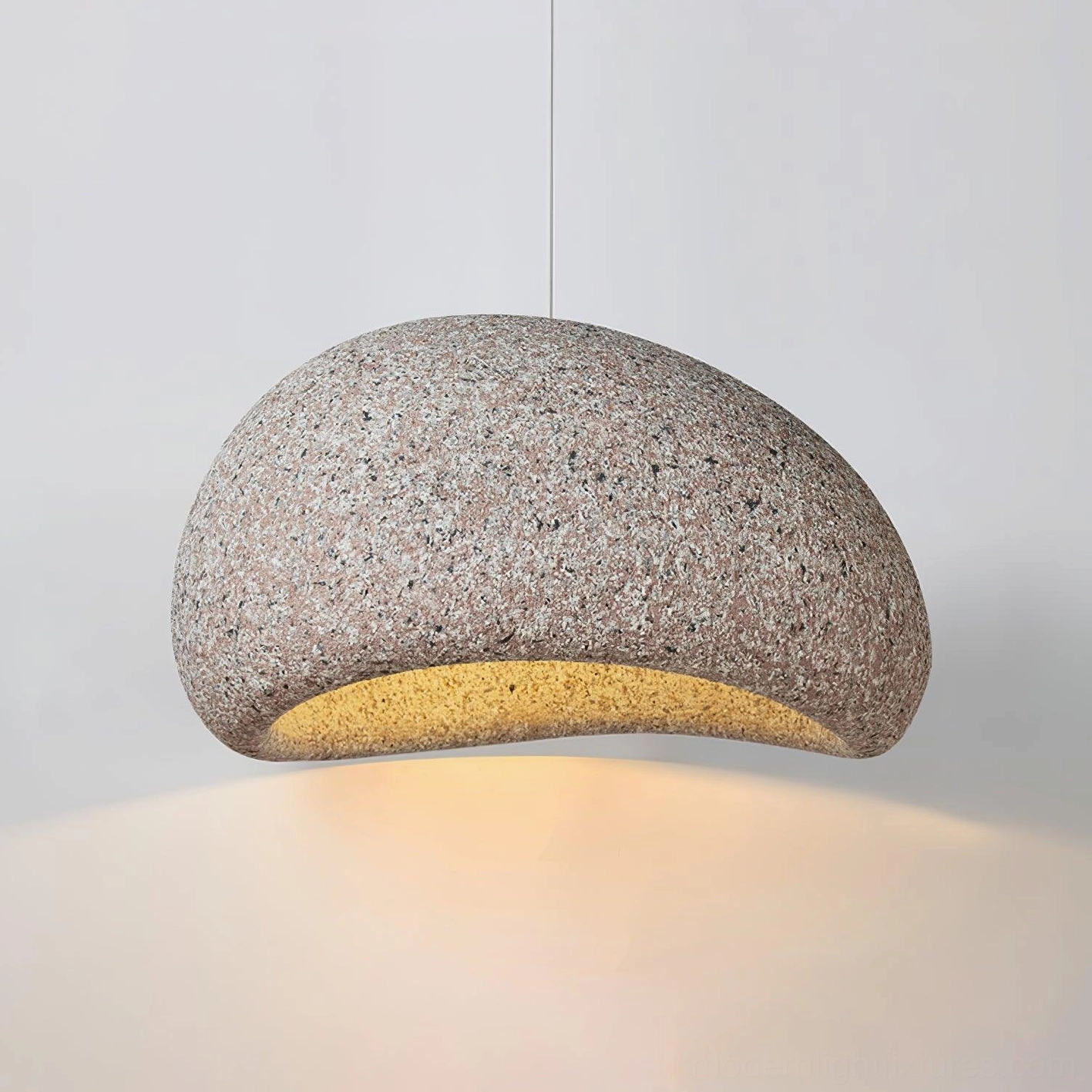 Close-up texture detail of Kioto pendant lamp showing fine granite-like speckled surface and warm illumination
