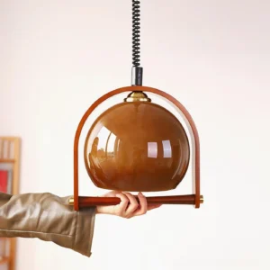 Kleine pendant lamp held in hand displaying semi-transparent brown glass shade and wooden support frame