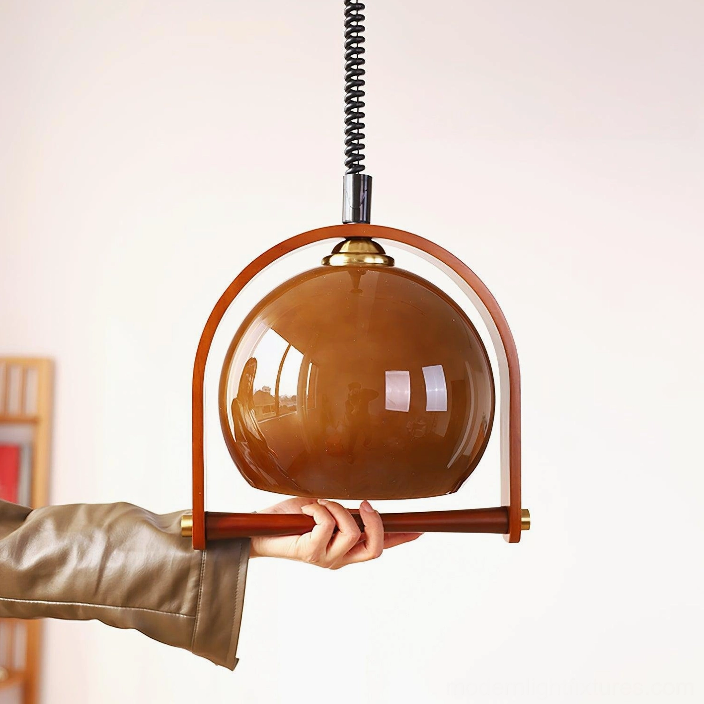 Kleine pendant lamp held in hand displaying semi-transparent brown glass shade and wooden support frame