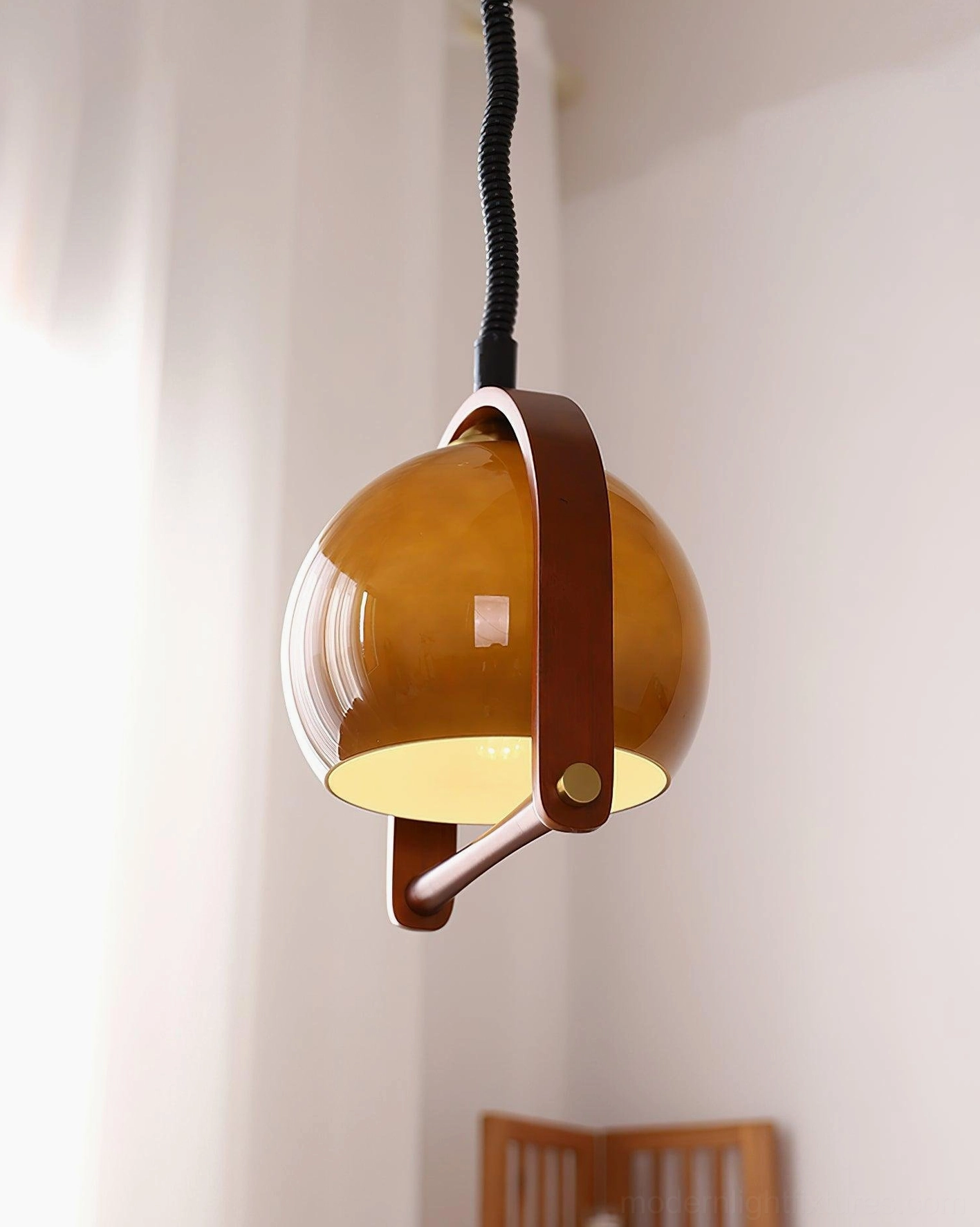 Kleine stretchable pendant light with semi-transparent brown glass in cozy bedroom corner with black coiled cord