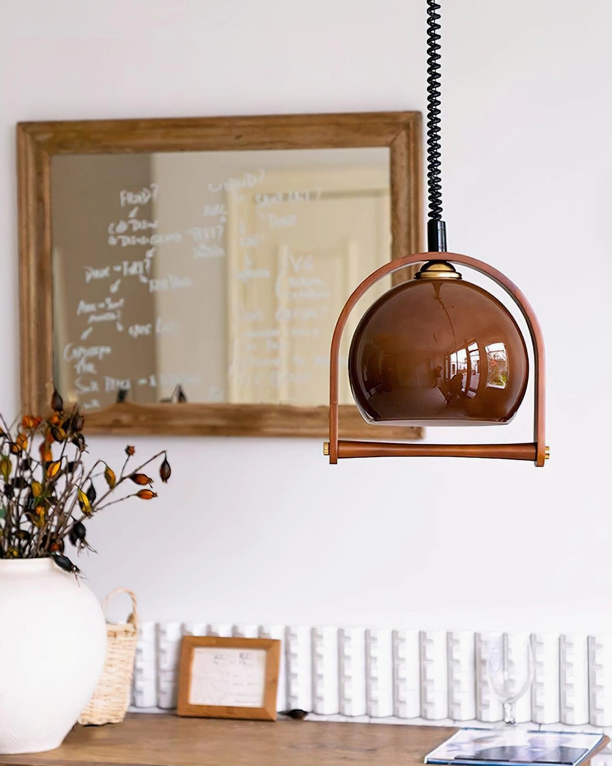 Kleine adjustable pendant lamp hanging in home study room with desktop decor and brown glass shade