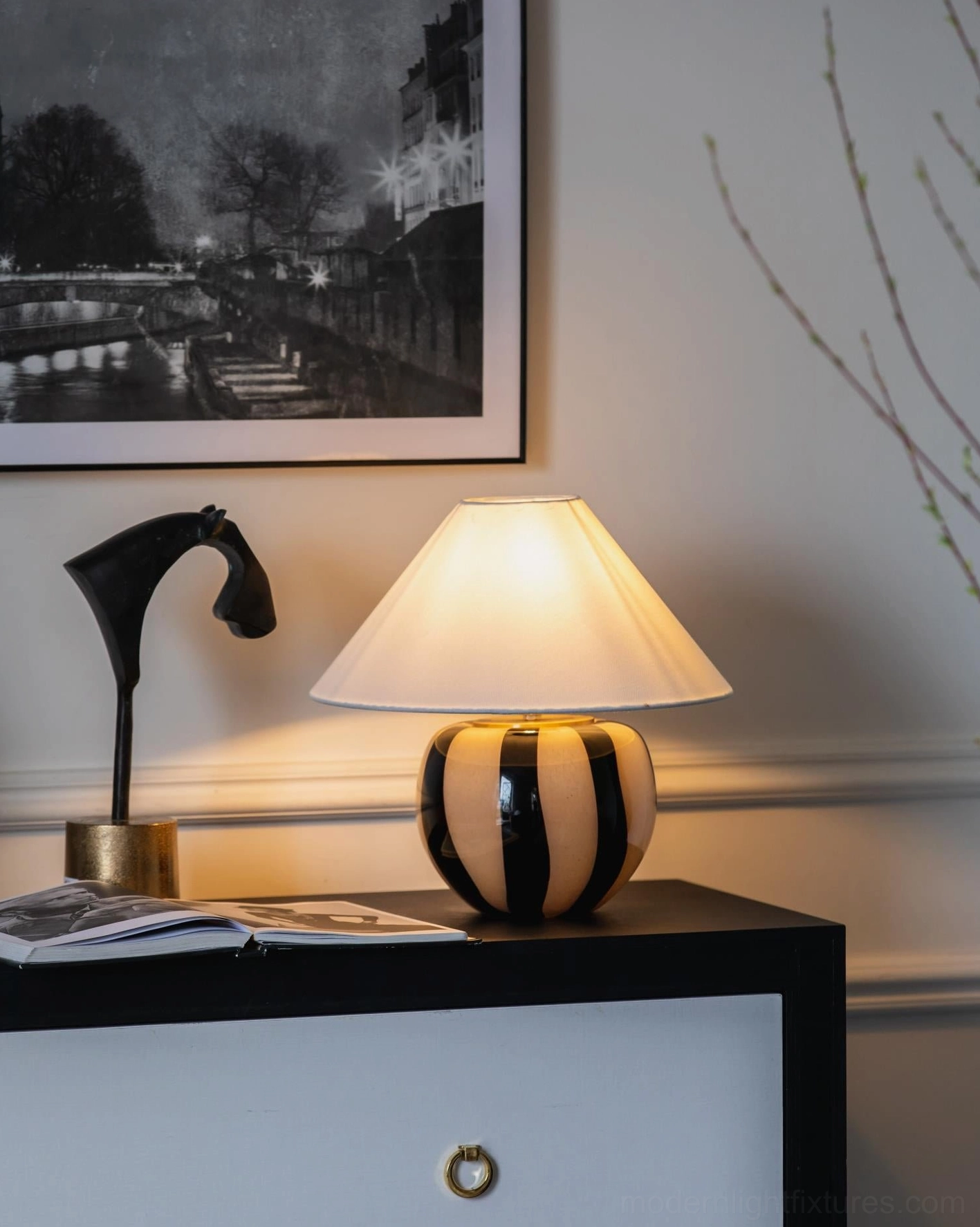 Kodhi contemporary table lamp illuminated on bedroom dresser with wall art and decorative objects