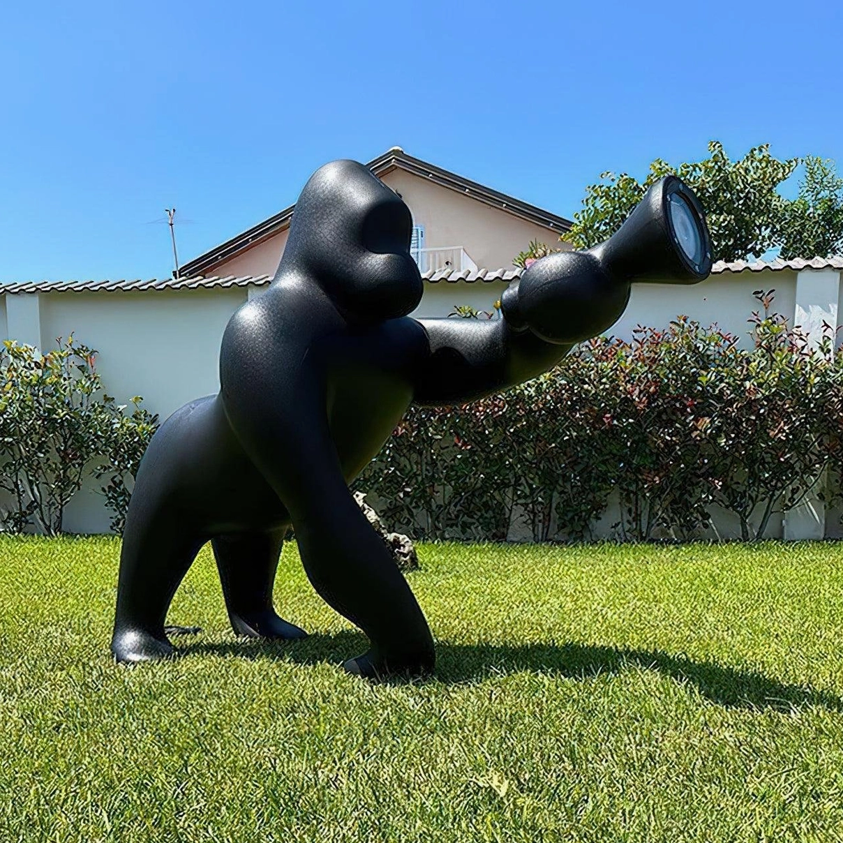 Black Kong floor lamp displayed outdoors on residential lawn, demonstrating versatile placement and bold visual presence in contemporary settings