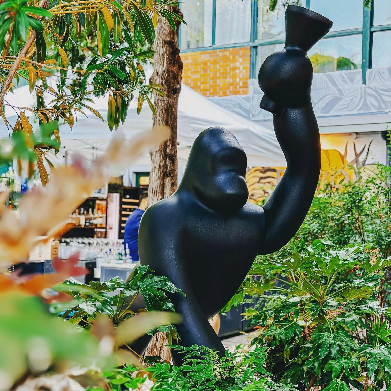 Kong floor lamp from low-angle front perspective in garden market setting, highlighting sculptural gorilla shape and decorative lighting functionality