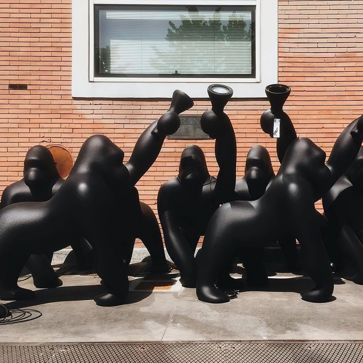 Group of multiple Kong sculptural floor lamps displayed on commercial building sidewalk, showing elevated view of artistic animal-inspired lighting collection