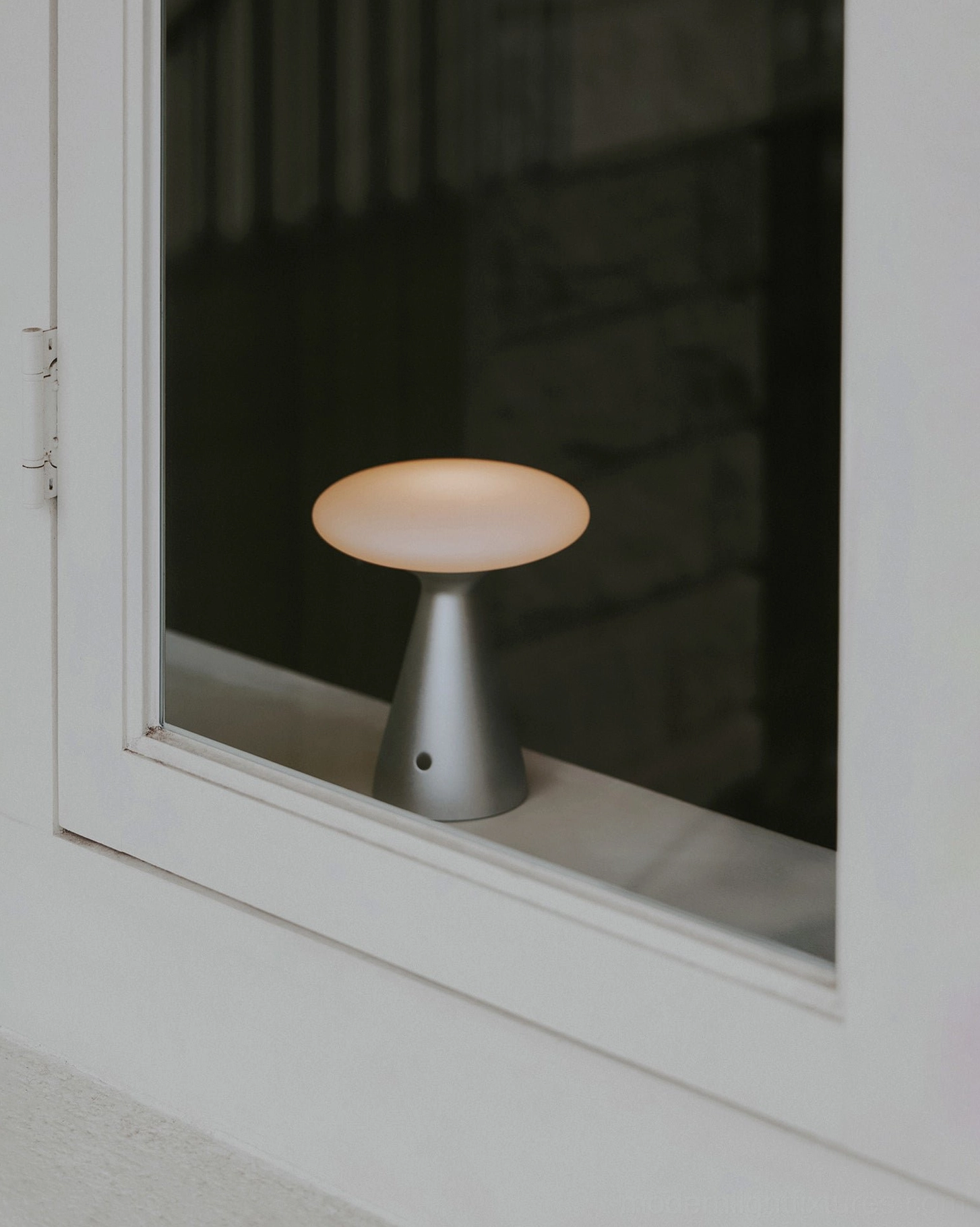 Konos table lamp interior window display with warm light reflection on white wooden window frame glass - lit illumination showcase