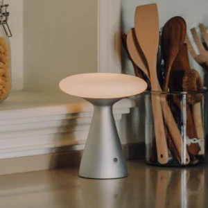 Konos modern touch control table lamp positioned on stone kitchen countertop next to wooden utensil holder and glass jar - nickel and white finish