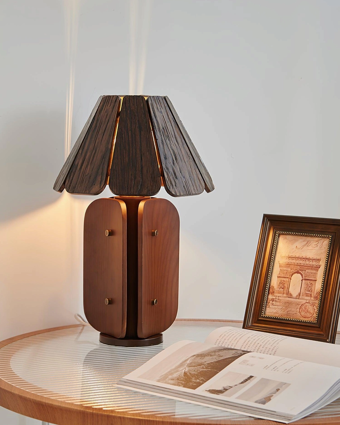 Kubec table lamp displaying warm light on glass side table with decorative items