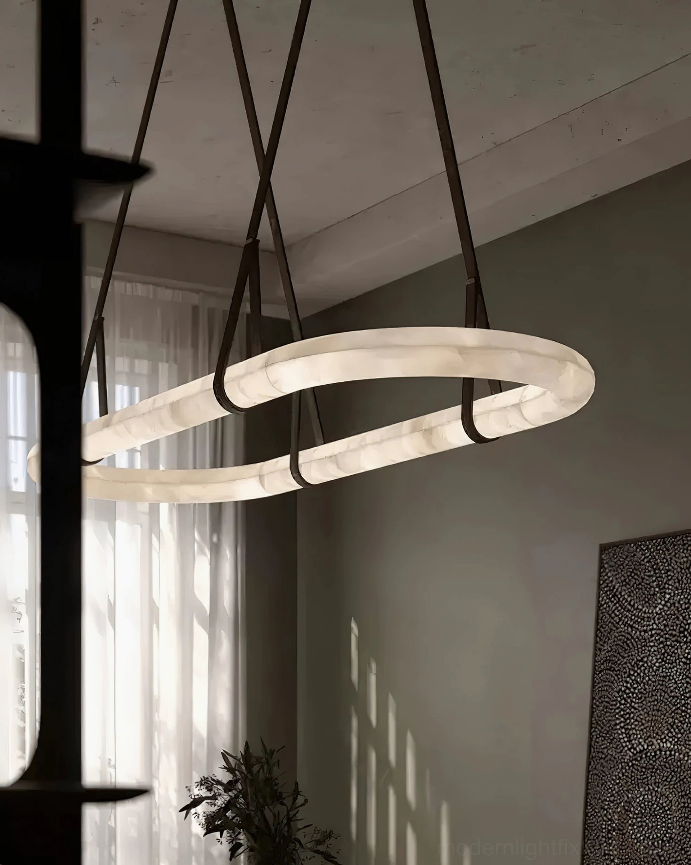 Dual oval alabaster pendant lights hanging side by side in modern dining area near sheer curtain windows with natural light