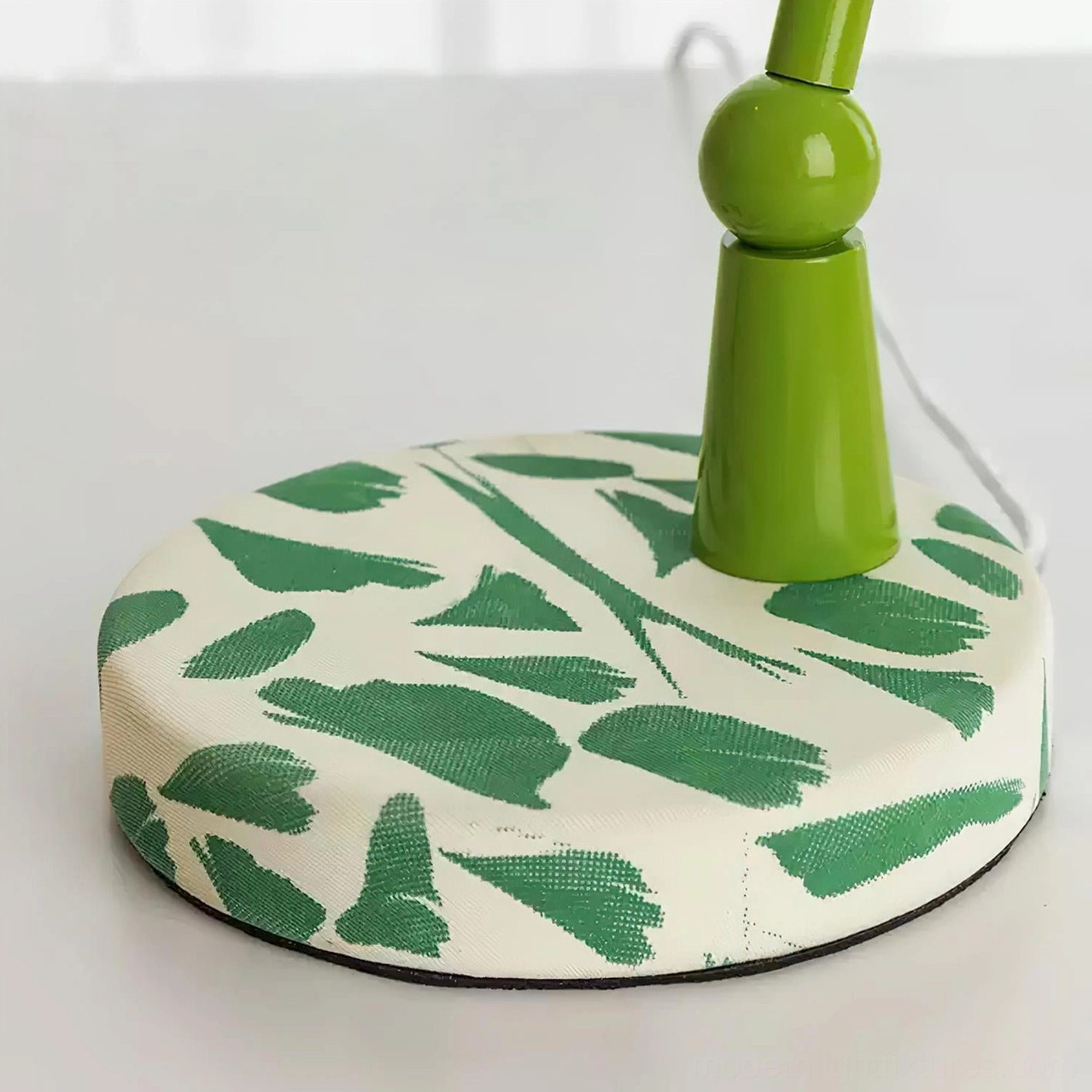 Close-up detail of artistic lampshade showing pink-green striped pattern with speckles on white fabric base