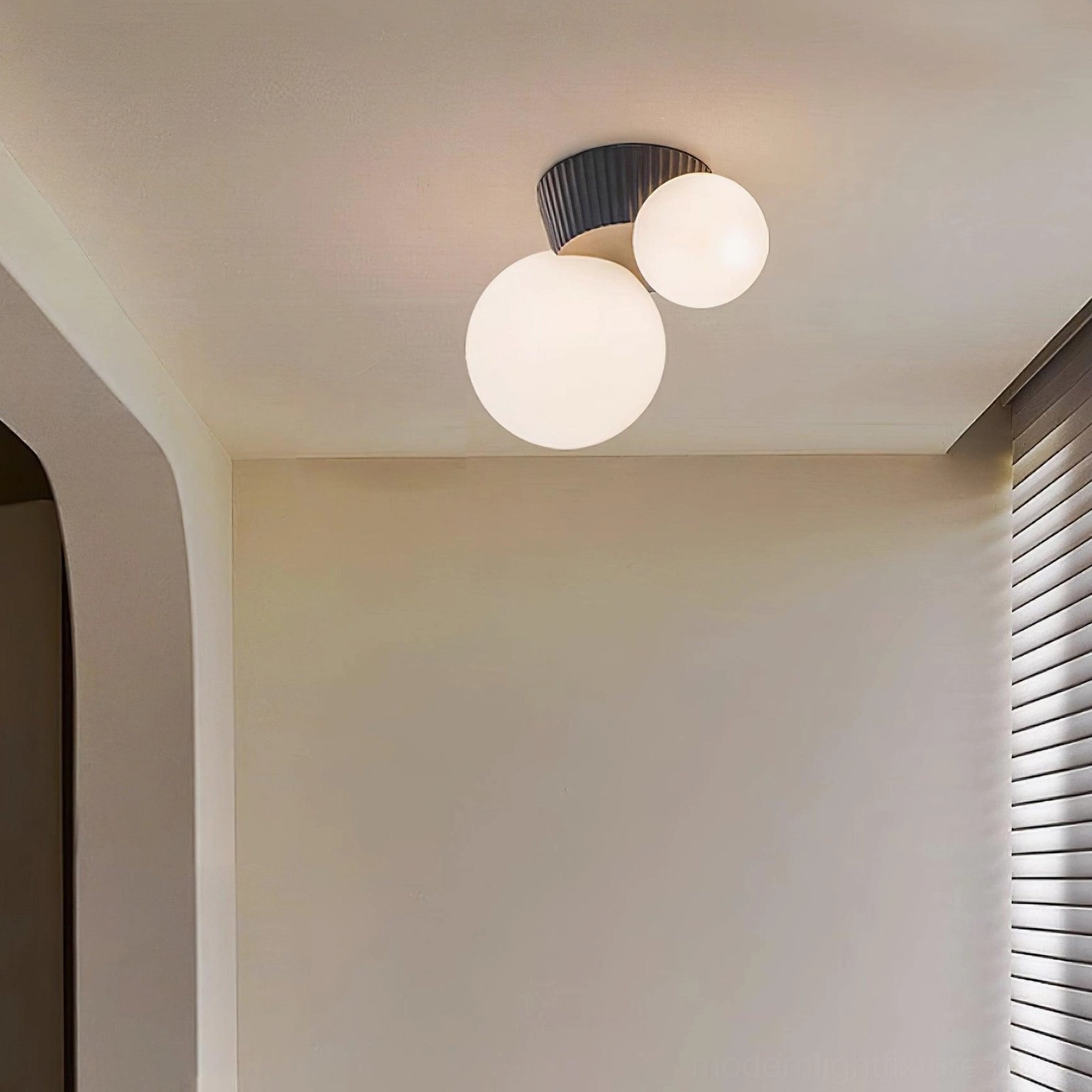 Land flush mount ceiling light with black ribbed canopy and spherical glass shades in home hallway