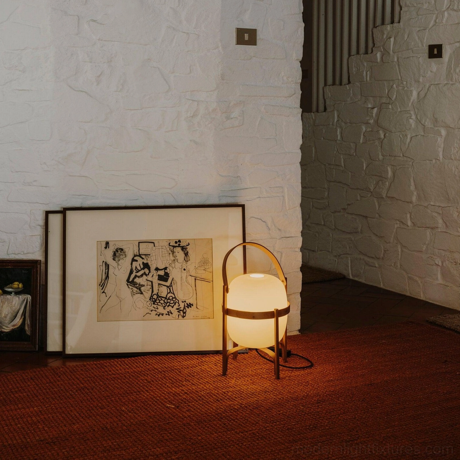 Portable lantern lamp in cozy rustic interior with red carpet and wall art