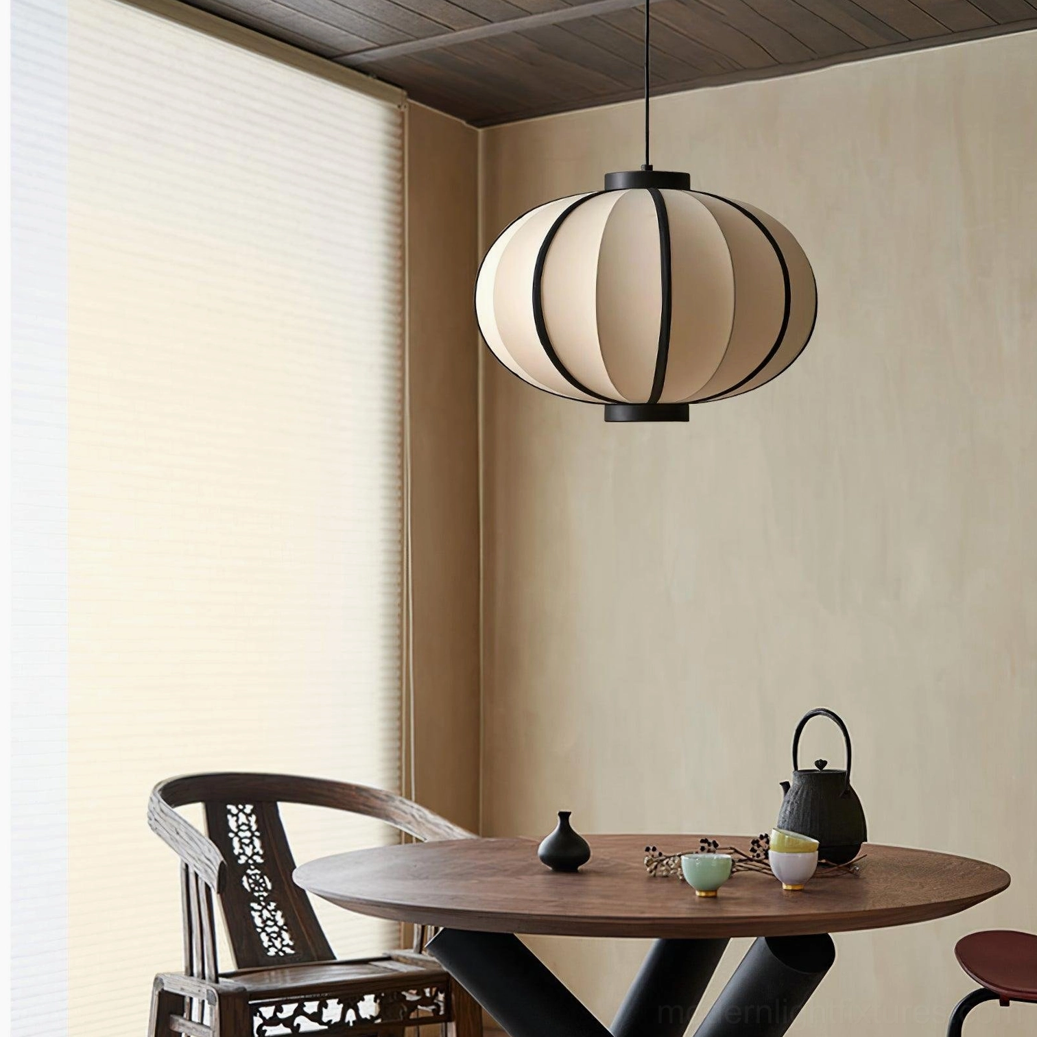 Black and white geometric pendant light installed above dining table in Asian-inspired interior