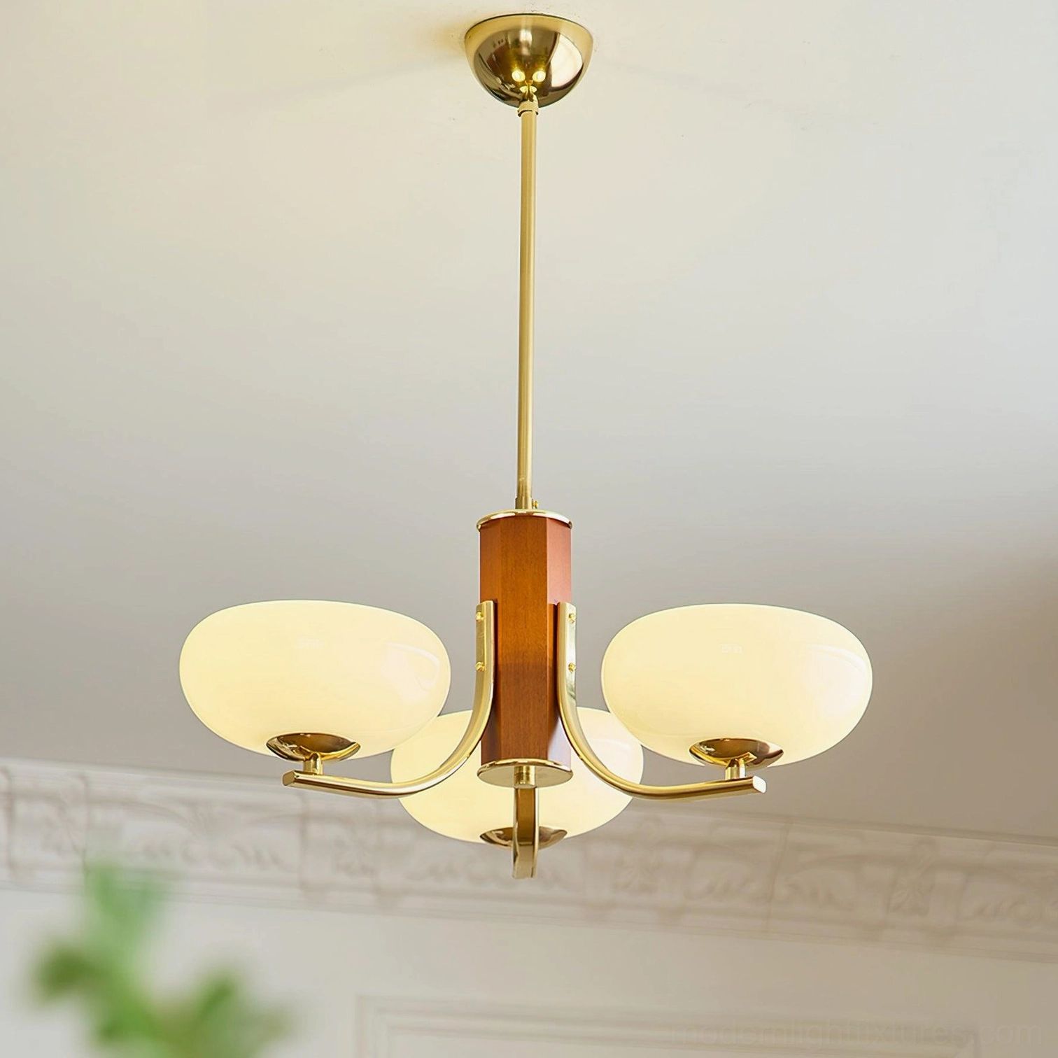 3-head minimalist mid-century modern chandelier with brass and wood mixed design in living room with carved ceiling and plants