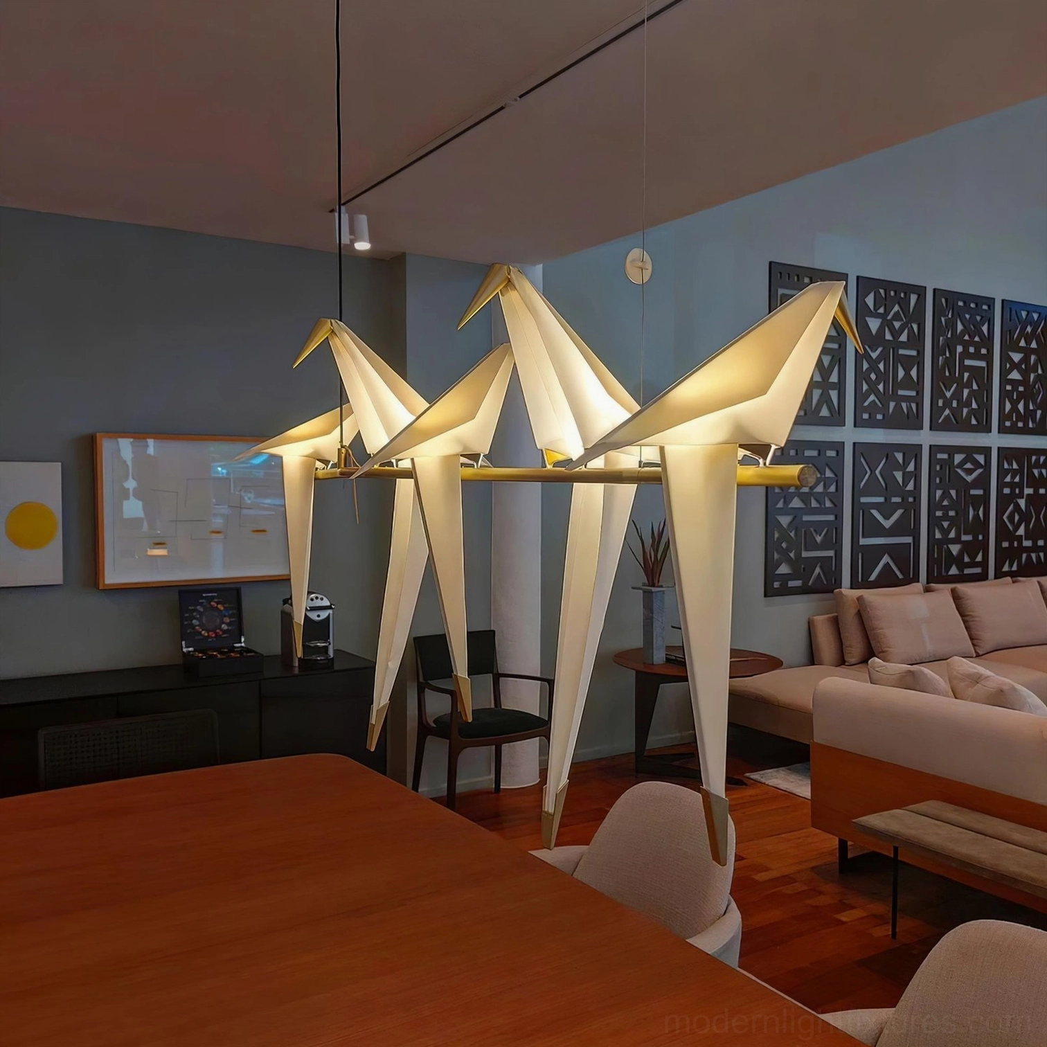 Large brass and white origami crane chandelier illuminating open-plan living dining space