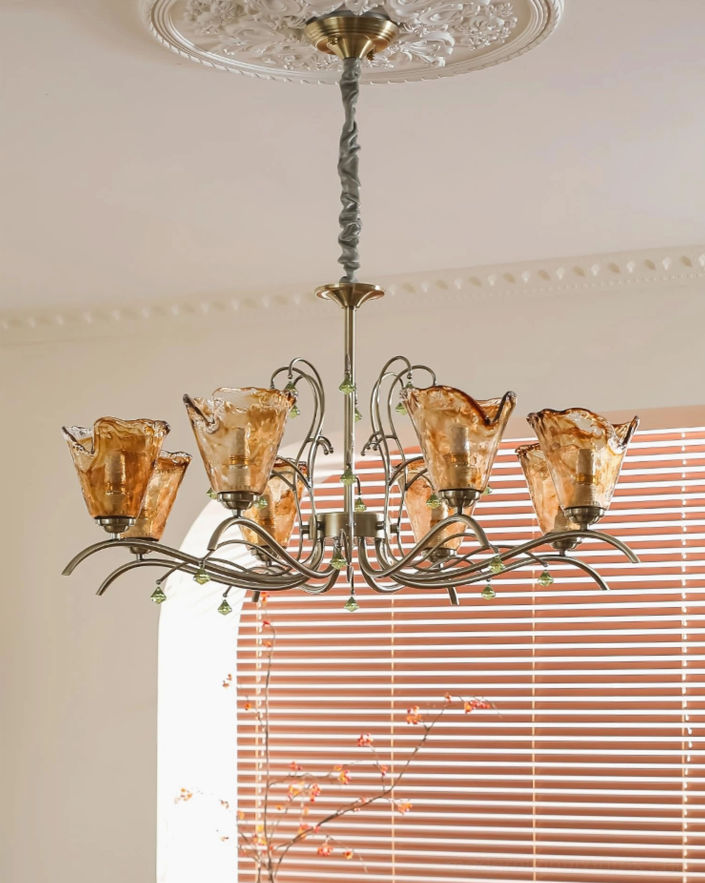 Large Vetraio multi-head chandelier installed in living room with arched blinds, upward ceiling angle view showing bronze twisted metal arms and carved ceiling rose