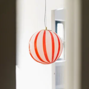 Large 30cm red striped spherical pendant light illuminated in residential interior showing warm ambient lighting