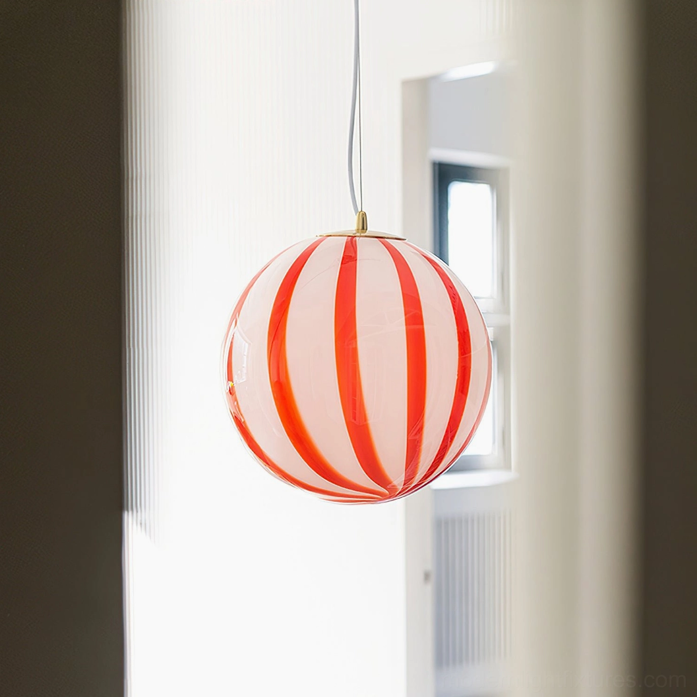 Large 30cm red striped spherical pendant light illuminated in residential interior showing warm ambient lighting