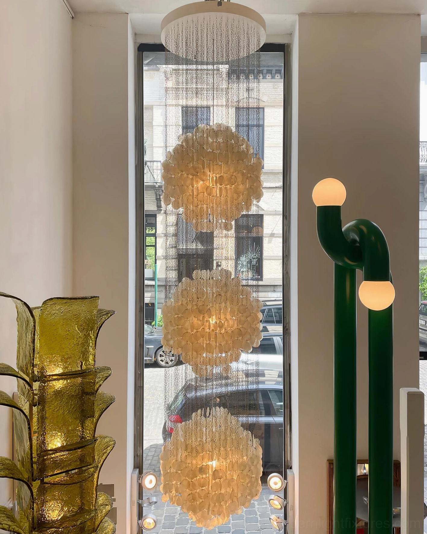 Large-scale shell chandelier pendant light in high-ceiling space creating dramatic architectural statement