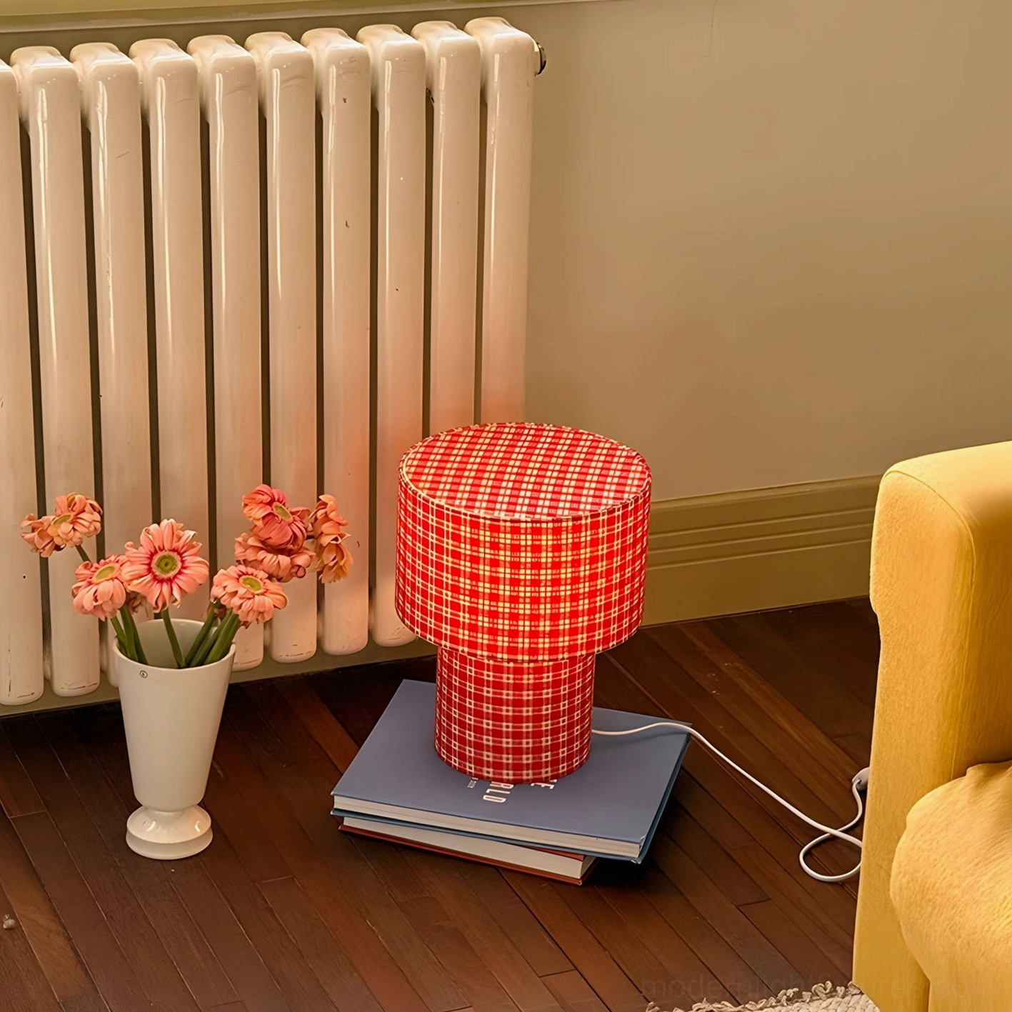Red gingham fabric table lamp placed on stacked books near radiator living room with yellow sofa decor