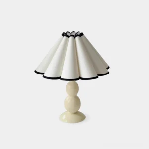 Lauren pleated table lamp with cream ceramic base and white fabric shade on white studio background