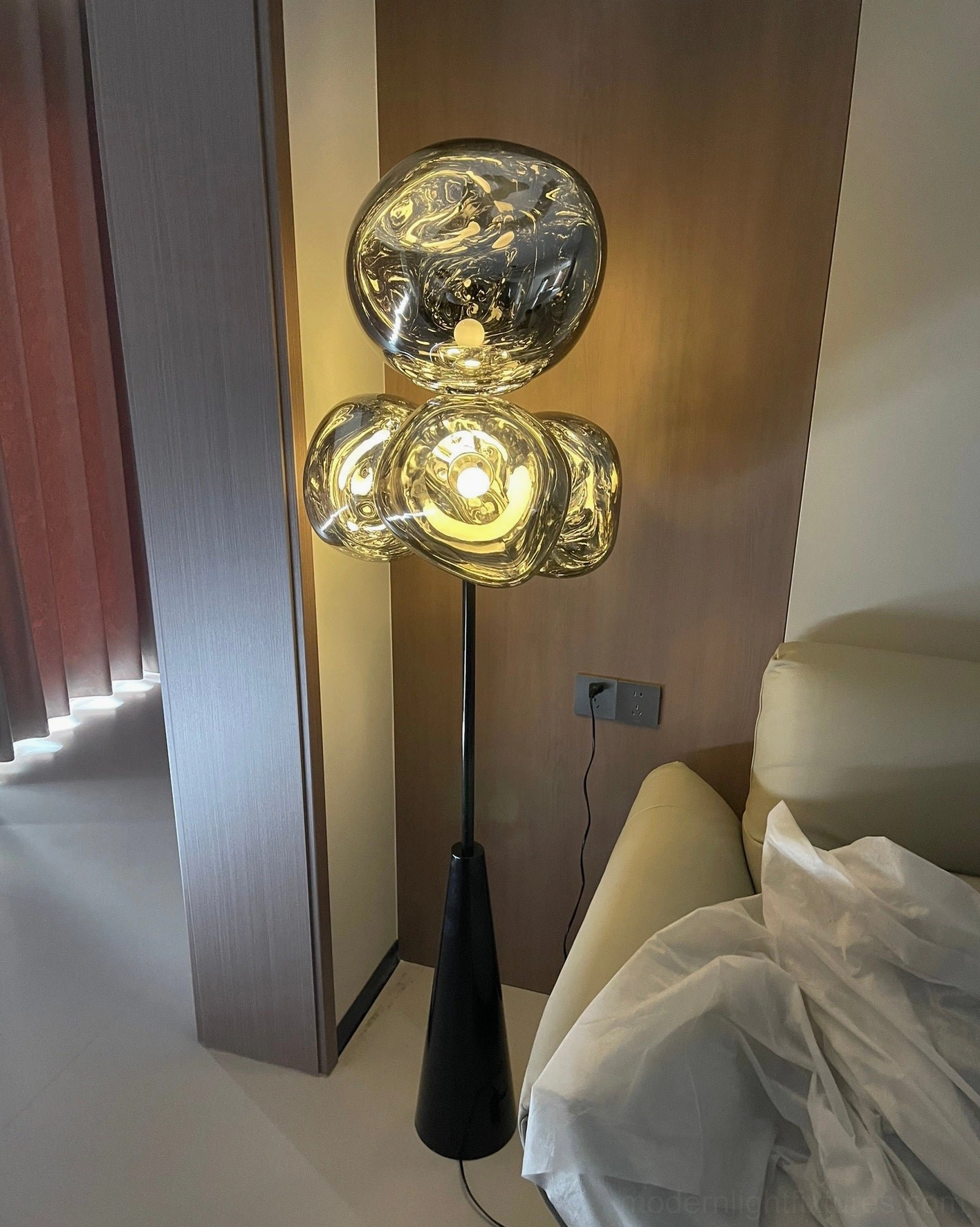 Lava Column floor lamp low angle view in modern bedroom corner with bright warm lighting - contemporary luxury decor