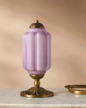 Lavender purple fluted glass table lamp with bronze accents displayed on marble tabletop interior setting