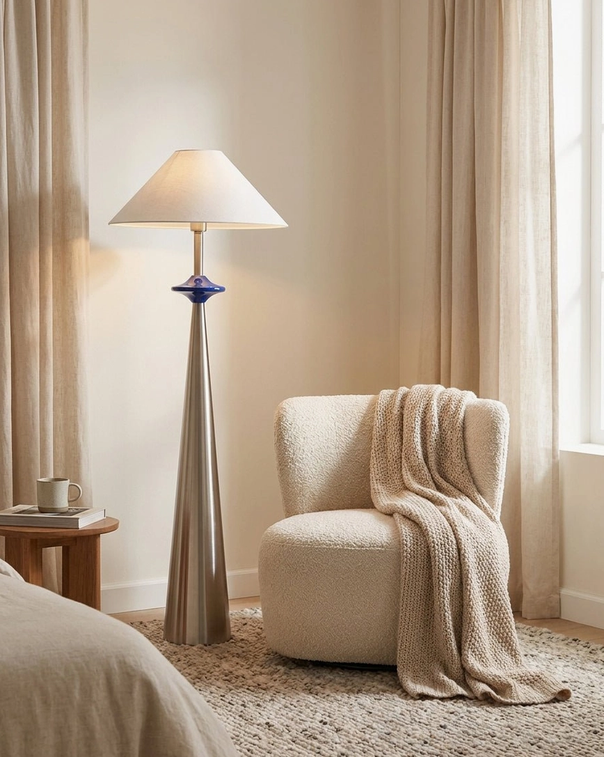 Cone floor lamp in cozy bedroom corner beside boucle armchair, creating warm ambient reading light, matte finish base