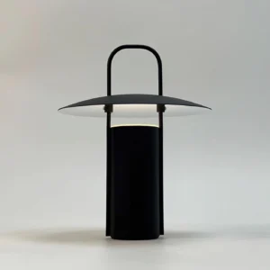 Illuminated portable LED table lamp emitting warm light with integrated handle on soft gray backdrop