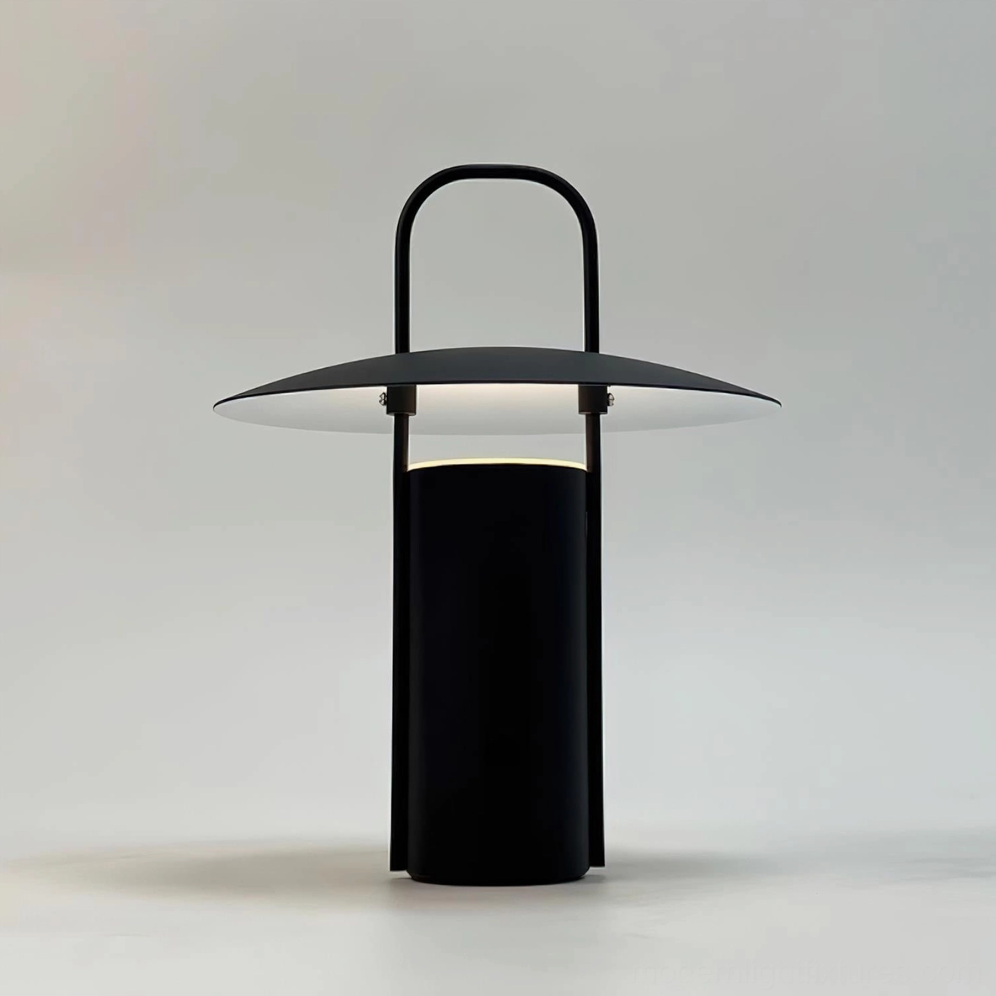 Illuminated portable LED table lamp emitting warm light with integrated handle on soft gray backdrop