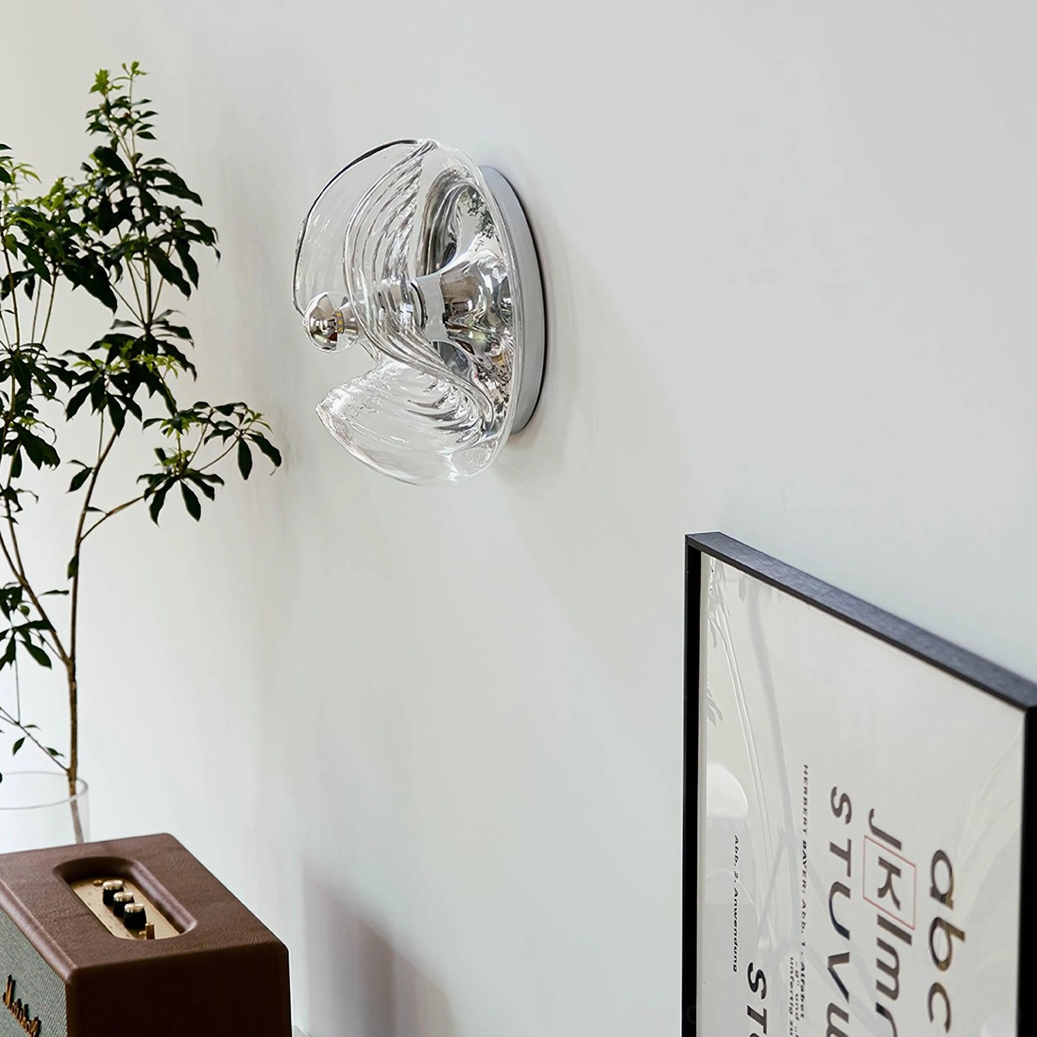 Wave glass wall sconce side view in minimalist home corner with green plants