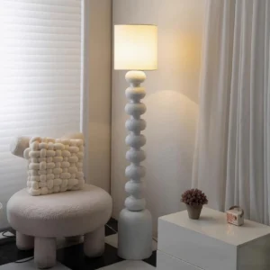 Leona contemporary floor lamp with textured resin base placed in modern living room with warm ambient lighting and boucle furniture