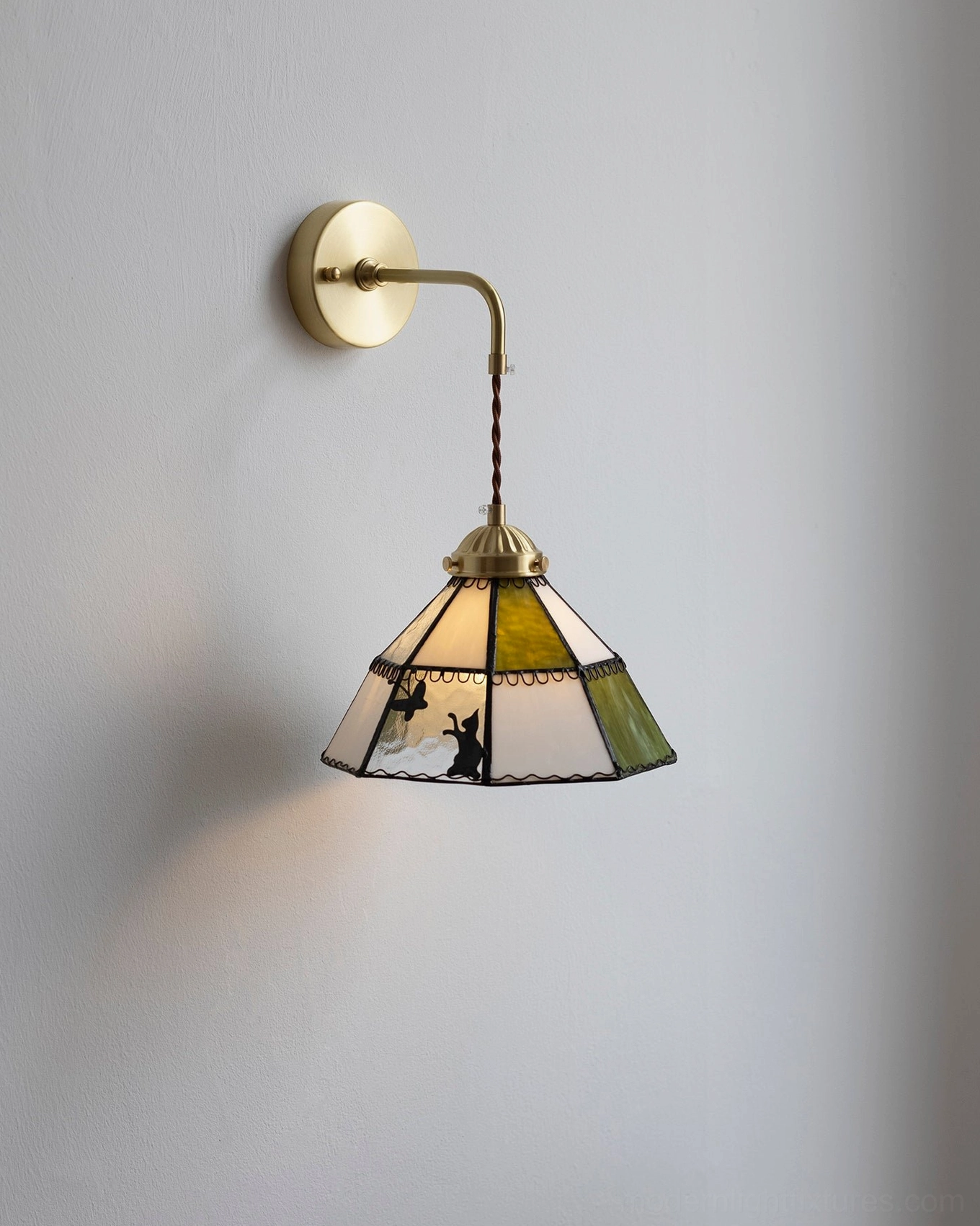 Lit stained glass wall sconce with curved brass arm and twisted cord detail