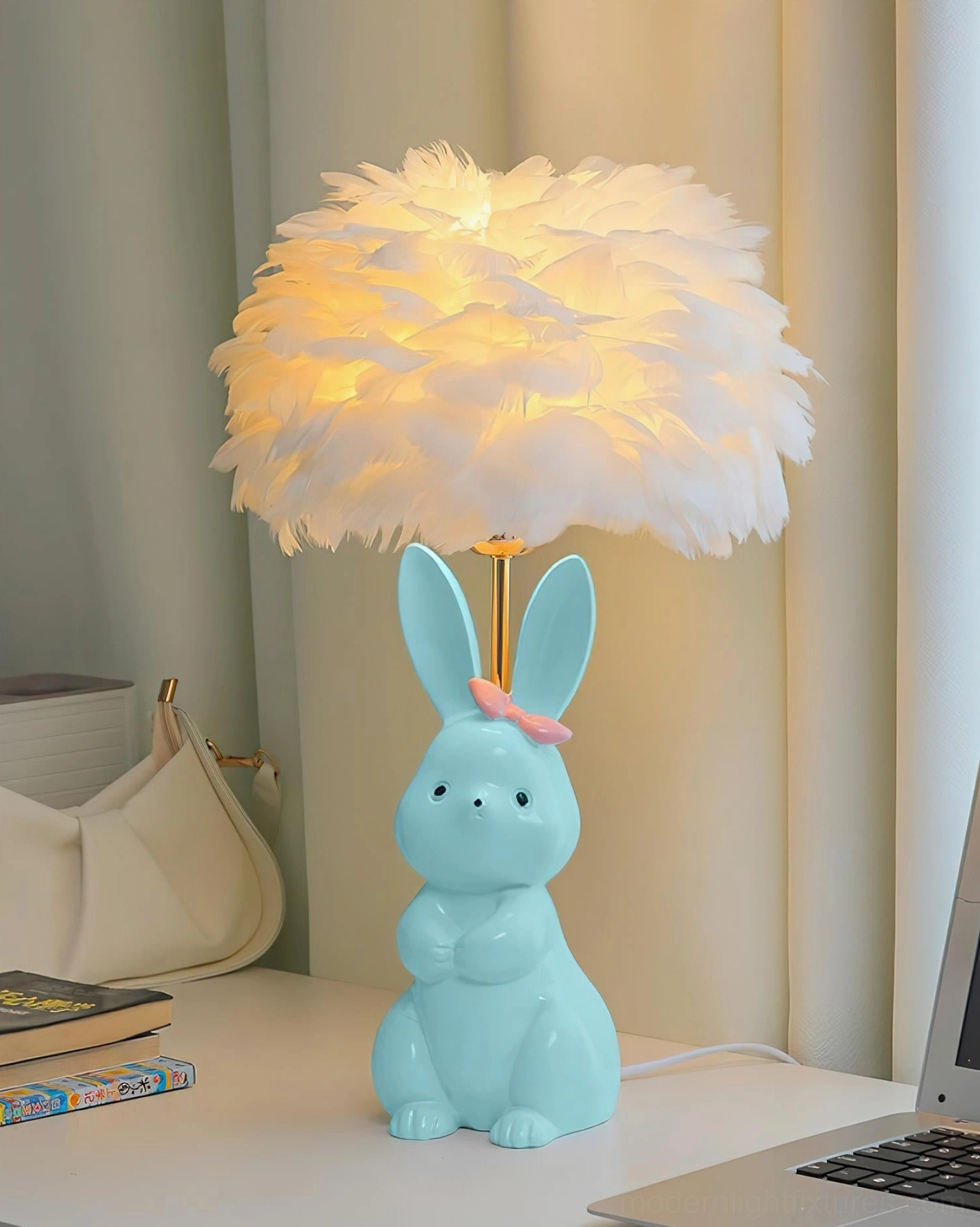 Light blue ceramic bunny lamp with lit warm feather lampshade and pink bow on home desk - angled view