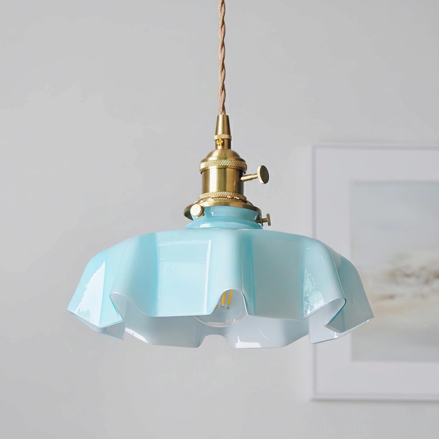 Light blue skirted ripple pendant lamp with visible exposed bulb and brass fixtures on minimalist wall background