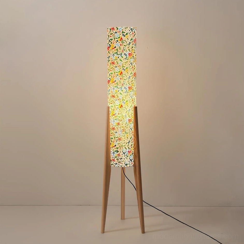 Natural light wood tripod floor lamp with warm glowing floral fabric shade in minimalist room, front flat view