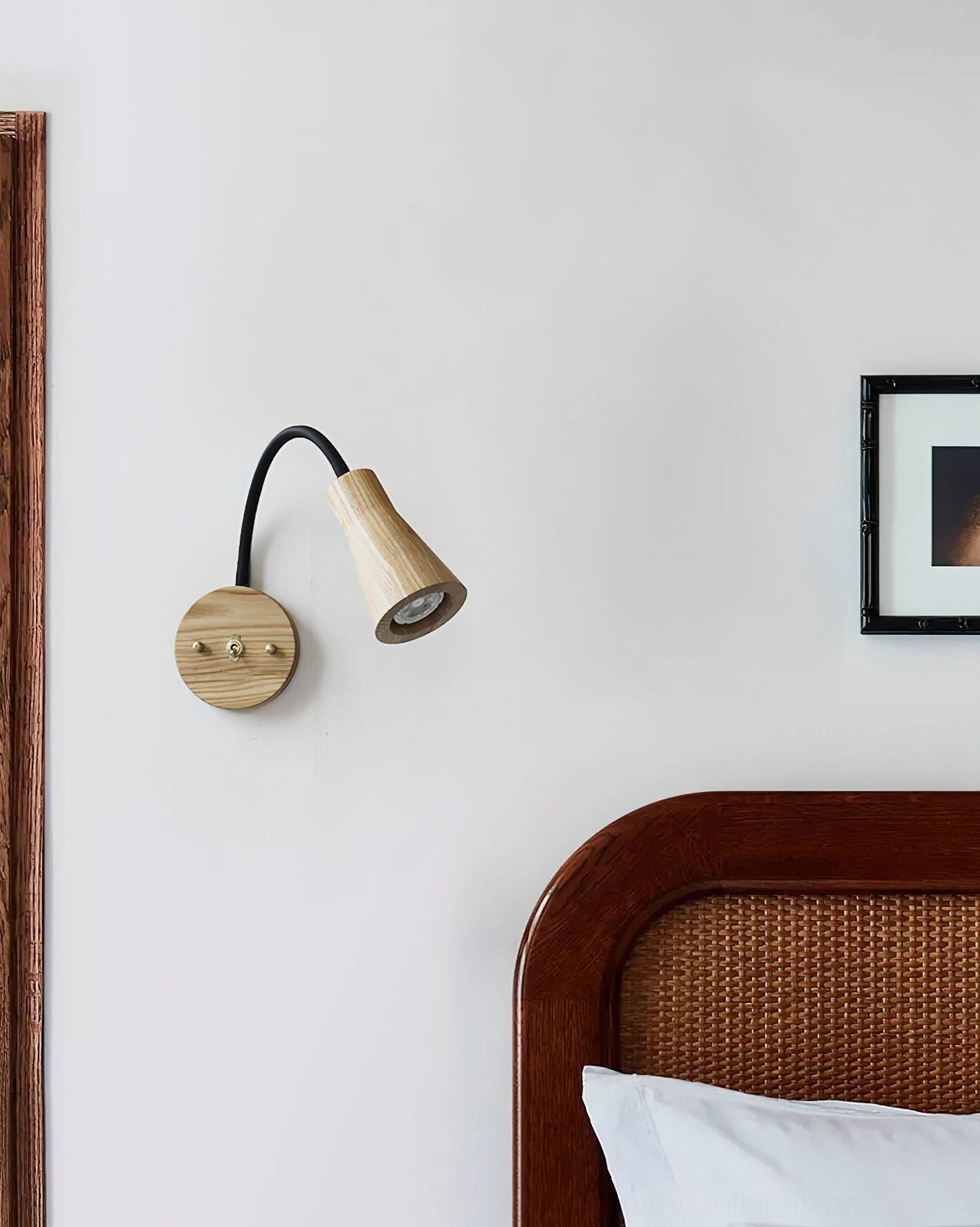 Light wood wall sconce mounted beside rattan headboard in modern bedroom, natural finish