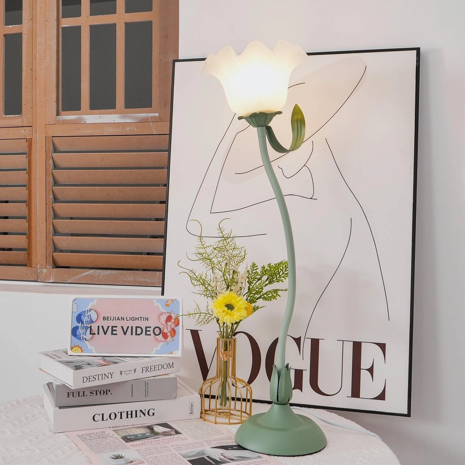 Modern lily flower table lamp with curved sage green arm in contemporary interior space