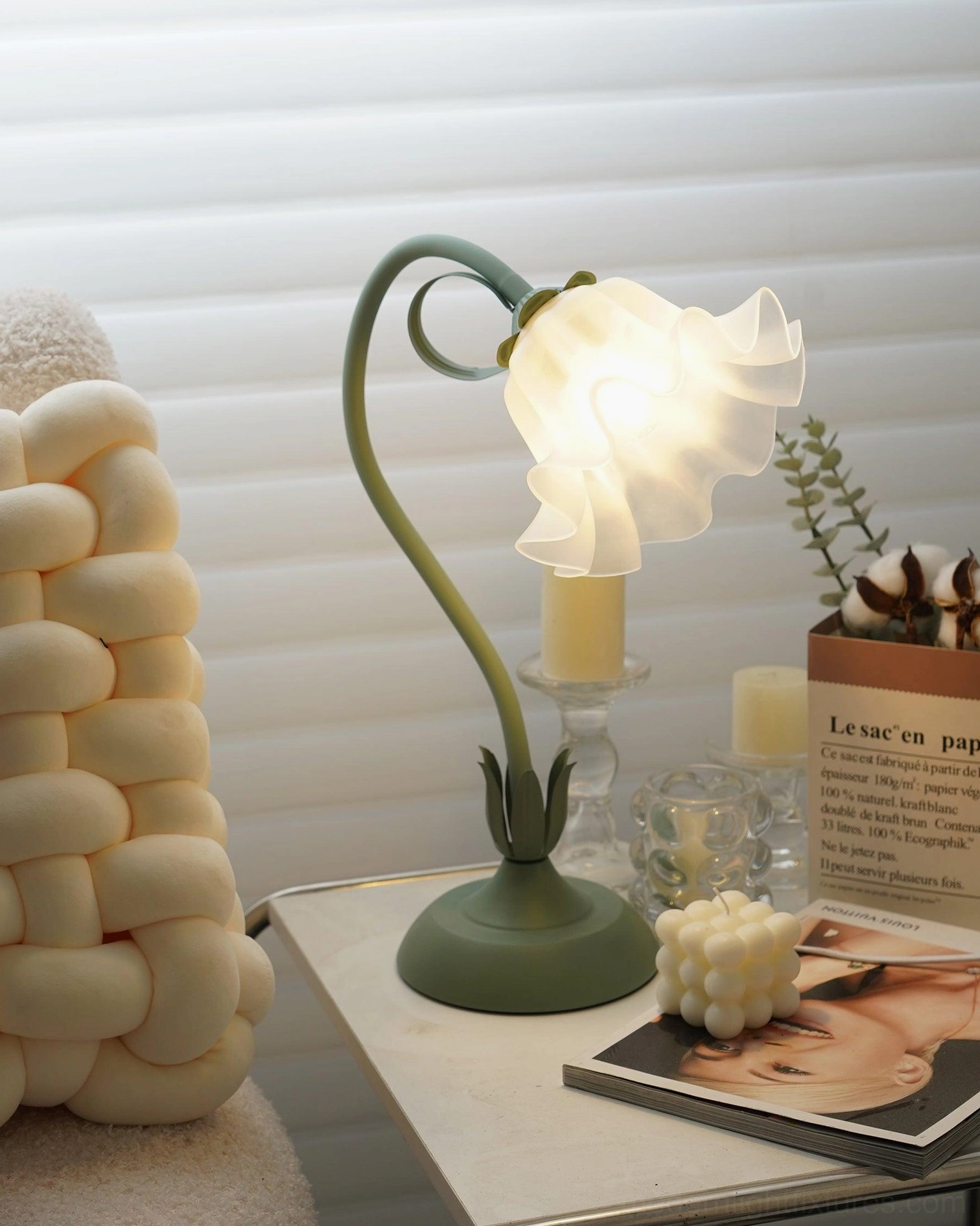 Sage green lily flower table lamp three-quarter angle on white side table with candles and magazines