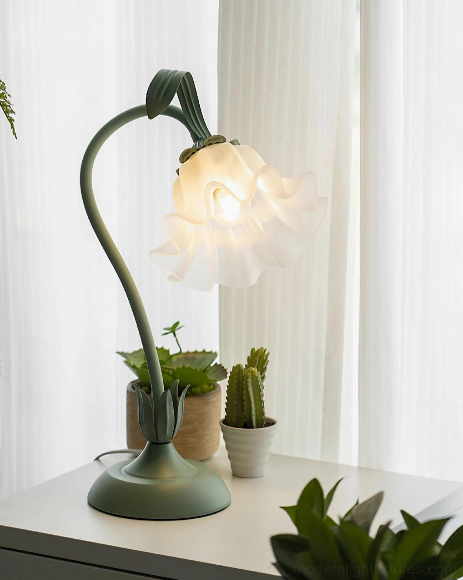 Botanical lily flower table lamp three-quarter view on home table with potted succulents and cozy decor