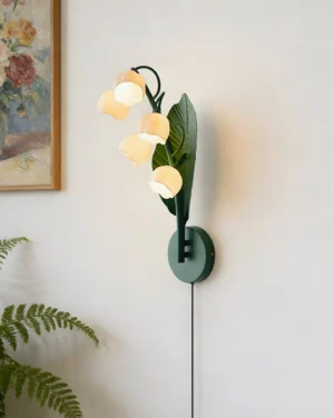 Modern wall sconce with lily of the valley flowers in bedroom with framed art and fern decor