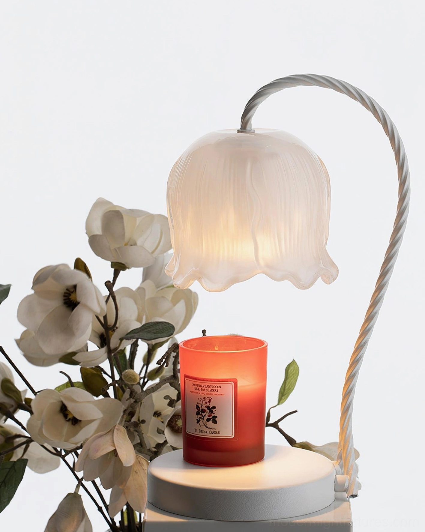 Lily of the valley candle warmer lamp with red scented candle and white flowers on desktop