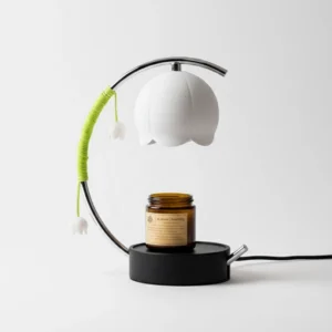 Modern botanical candle warmer table lamp in chrome and white finish displayed from right front three-quarter angle with visible power cable