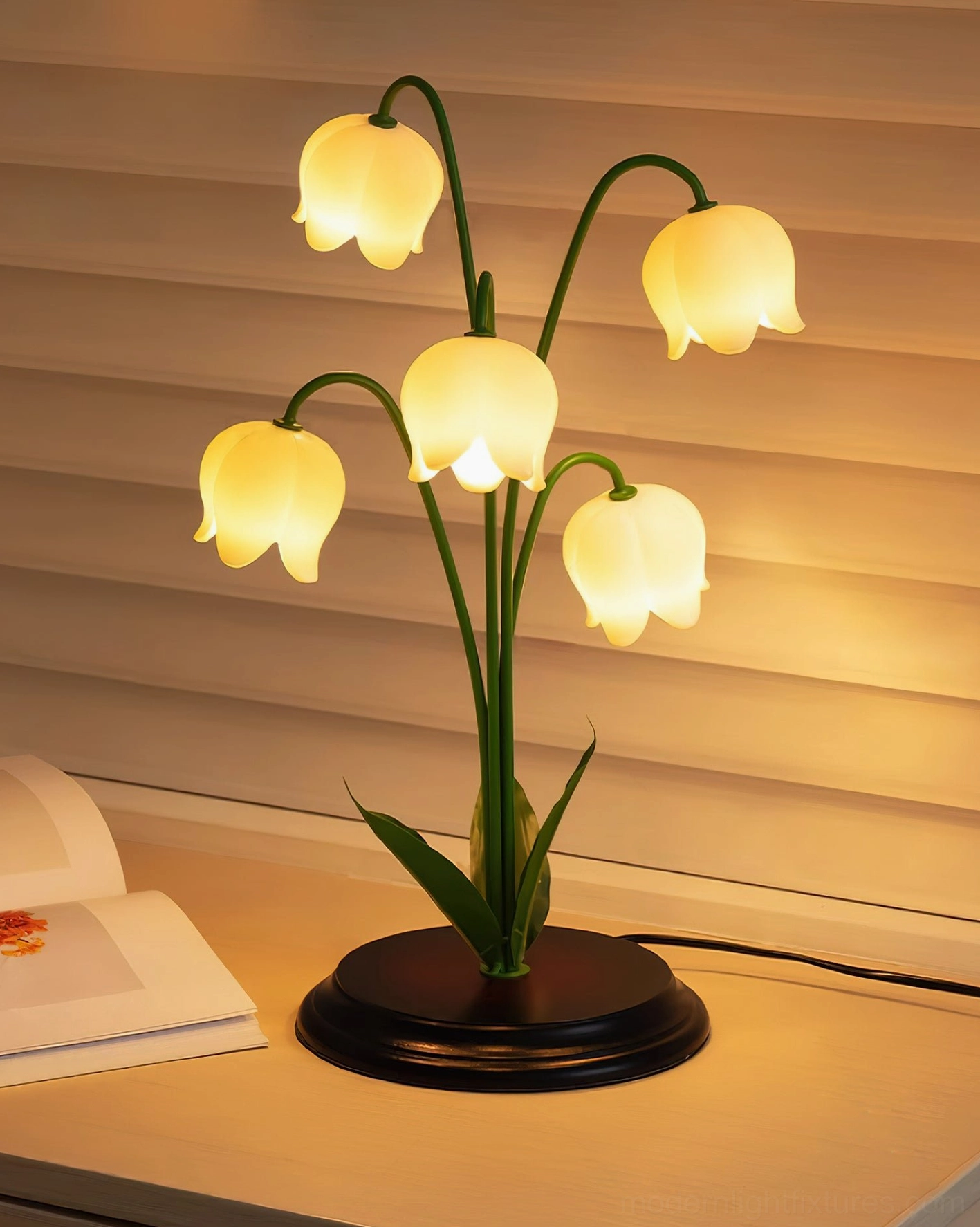 Modern table lamp with five glowing lily flower heads and green stems on desk