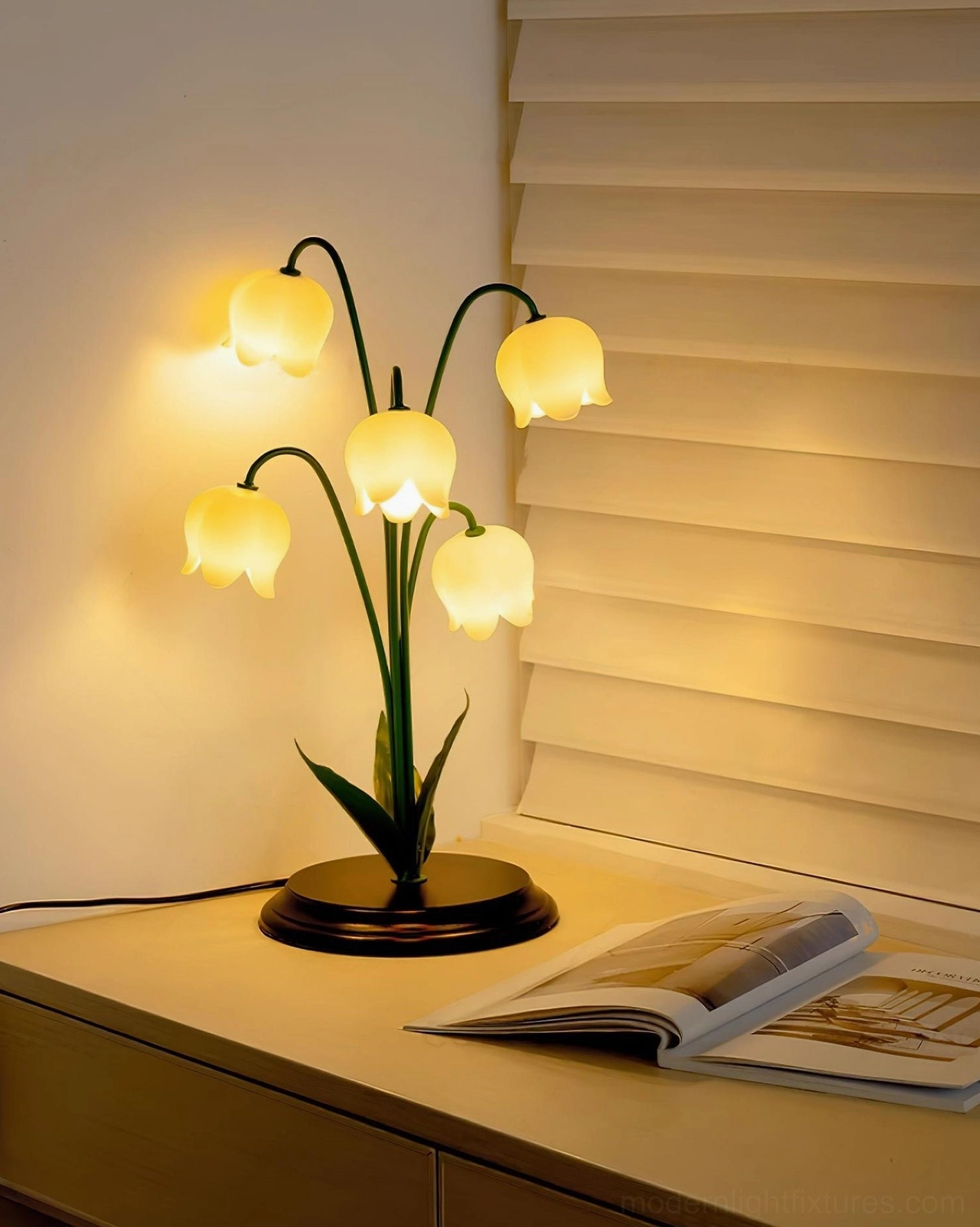 Lily of the Valley decorative table lamp on wooden desk with magazines and window blinds