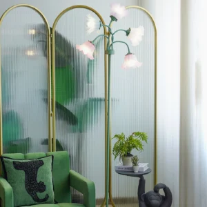 Pastel floral floor lamp with brass-green frame creating warm ambient lighting in modern living room with velvet green sofa