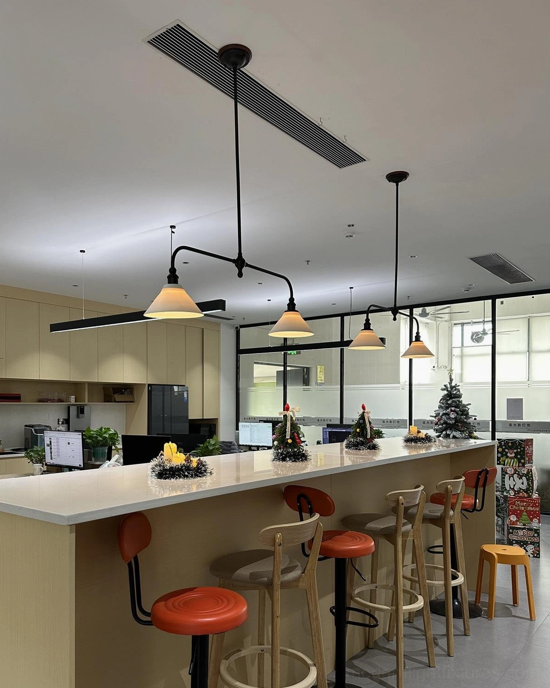 Linear chandelier with aged brass finish and white ceramic shades creating warm ambient lighting in residential kitchen