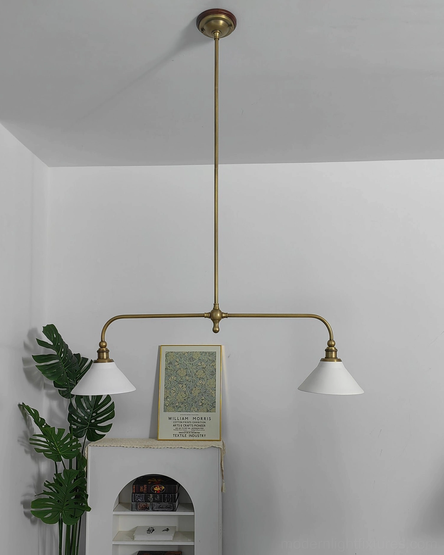 Two-light linear chandelier featuring aged brass frame and ceramic shades in warm kitchen setting with vintage charm